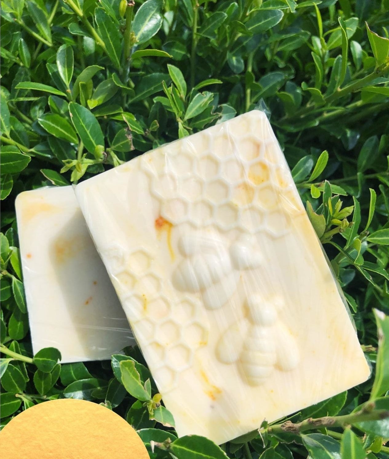 A white and yellow streaked bar of soap imprinted with bees and honeycomb patterns 