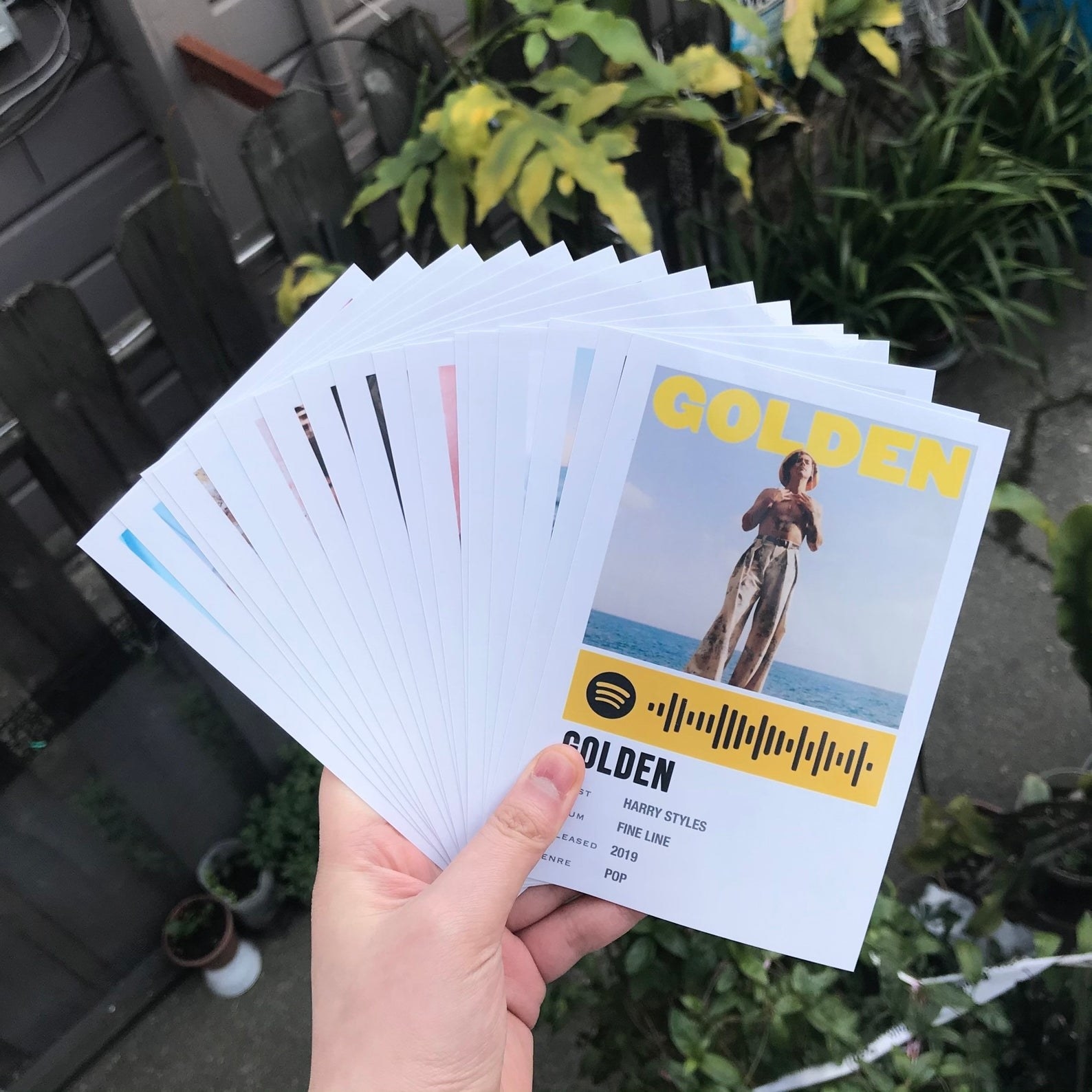 A model holding the photo-sized prints, which feature photos of Harry Styles to go with each song 