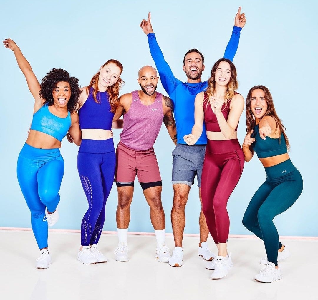Six instructors in athletic wear smiling and posing together