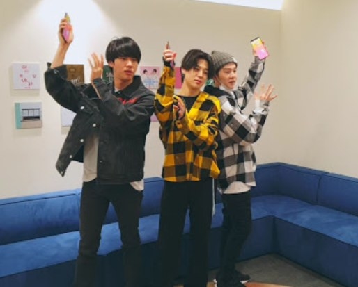 Jin, Jimin, and Suga play a dance game in front of a couch