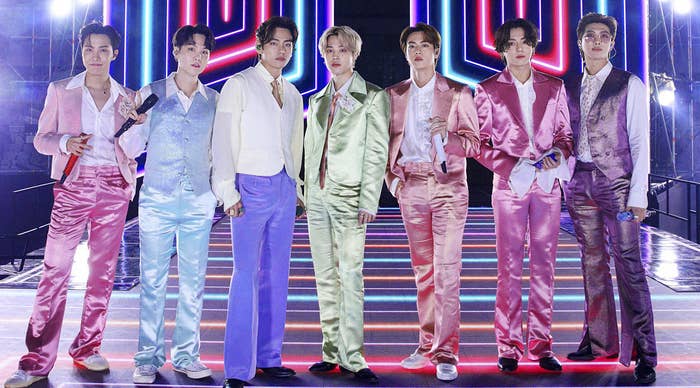BTS wears colourful satin suits standing in a line on a lit-up stage