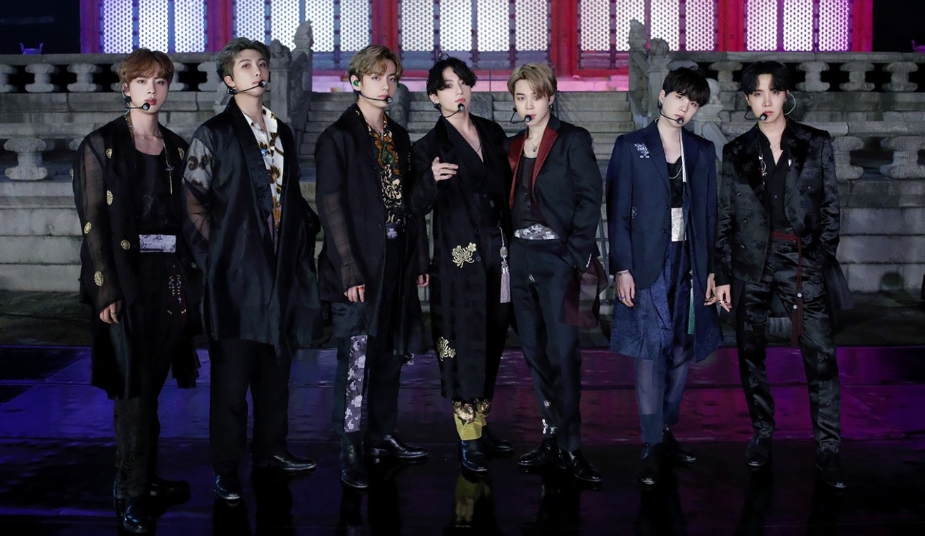 BTS wear traditional Korean clothes and stand on stage in front of a palace