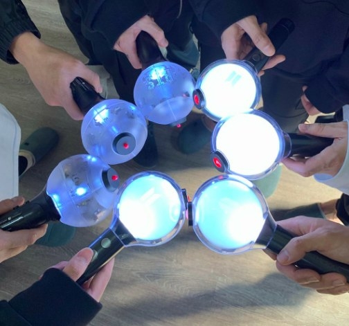 A close up of BTS&#x27; hands holding ARMY bombs (their light sticks) 