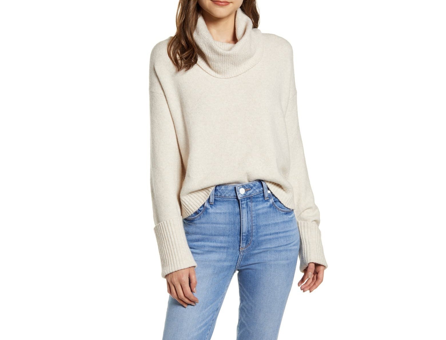 Model wearing the cream sweater tucked into jeans