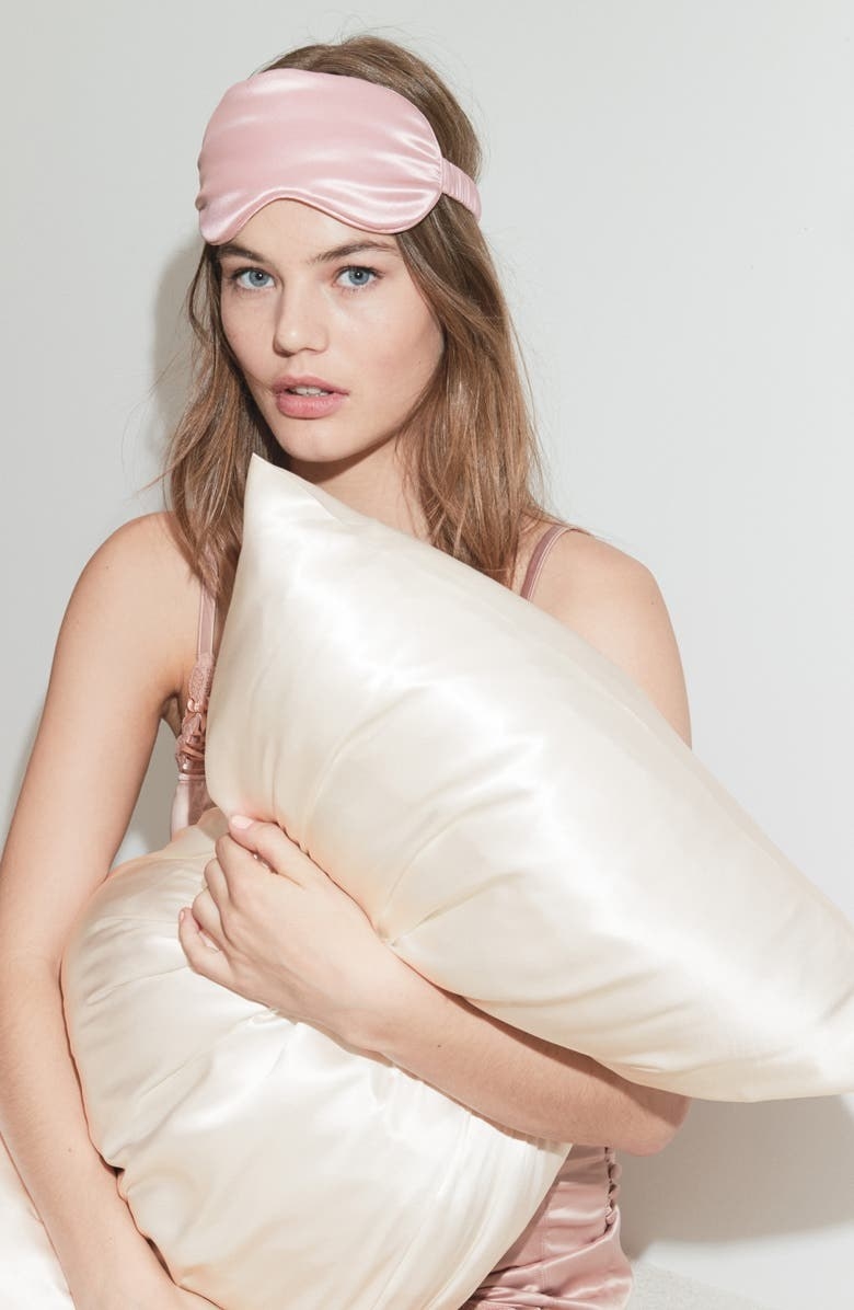 Model wearing a pink silk sleep mask and white silk pillowcase
