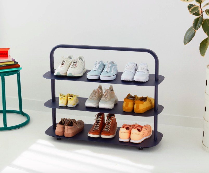 Three-tiered blue shoe rack with nine pairs of shoes displayed 