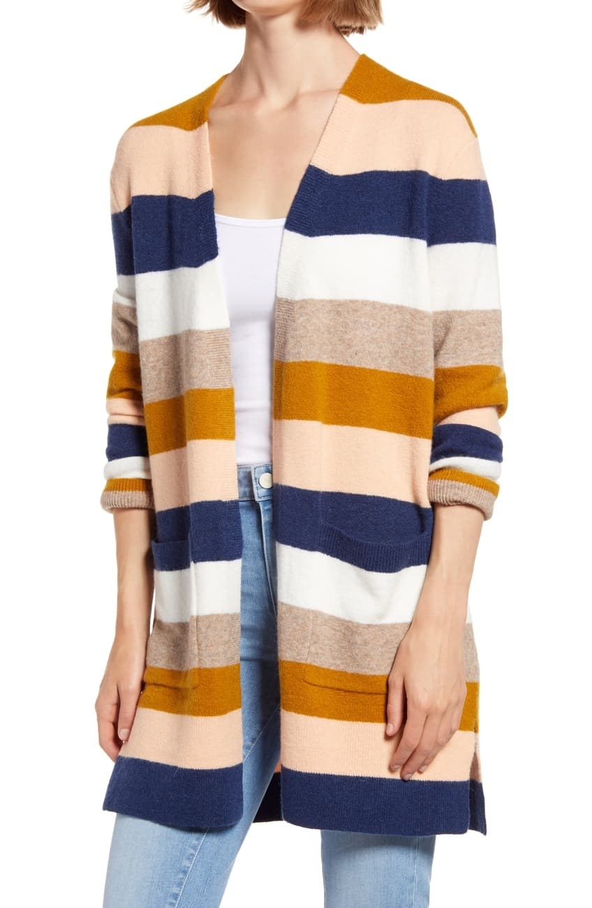 a model wearing the cardigan with orange tan, light pink, white, and navy vertical stripes