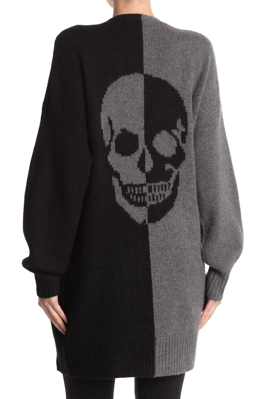 a model in a sweater that is black on one half and gray on the other with a skull in the middle