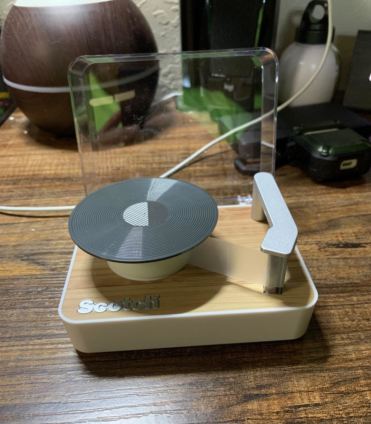 tape dispenser with the roll on the record part and the end of the tape stuck to the needle part, there&#x27;s even a cover that goes up and down 