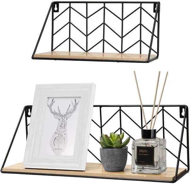 two shelves with a natural wood base and black metal backing in a chevron design