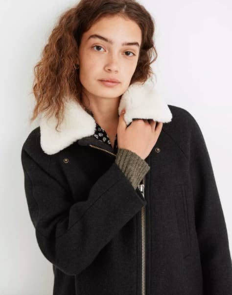 Model wearing heavy navy coat with zip up and sherpa collar