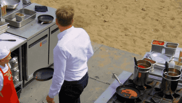 A GIF of someone throwing a pan into the sand