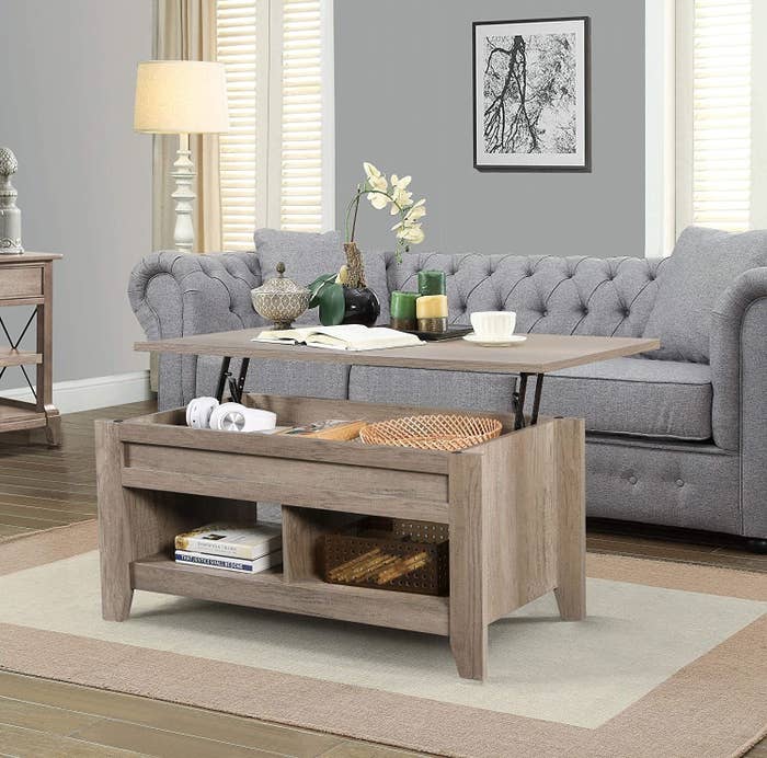 the light wood coffee table with the top lifted to show the storage inside