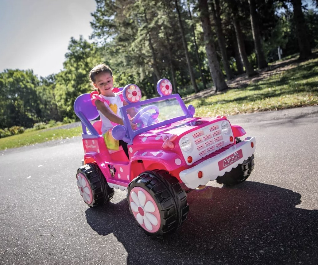 A person riding the pink Minnie Mouse car