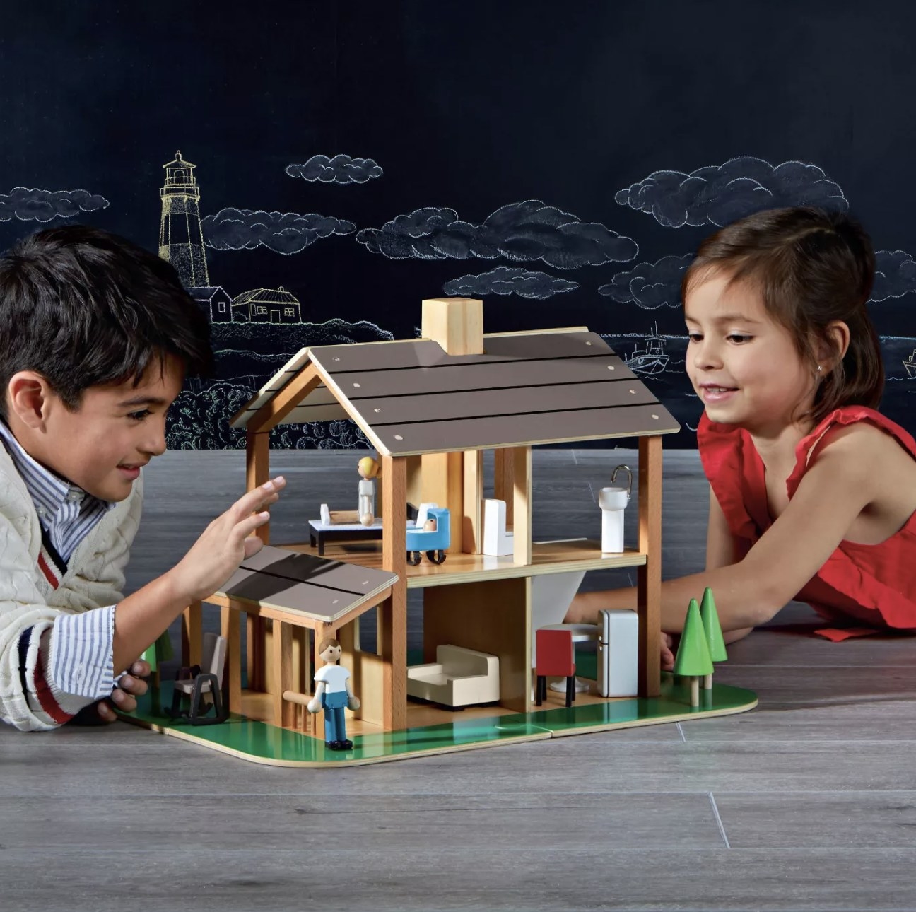 Two people playing with a wooden dollhouse