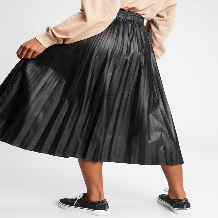 a model turned to show the back of the black faux leather skirt