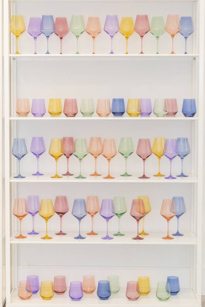 Cabinet holding a mixture of stemmed and stemless wine glasses in a variety of colors
