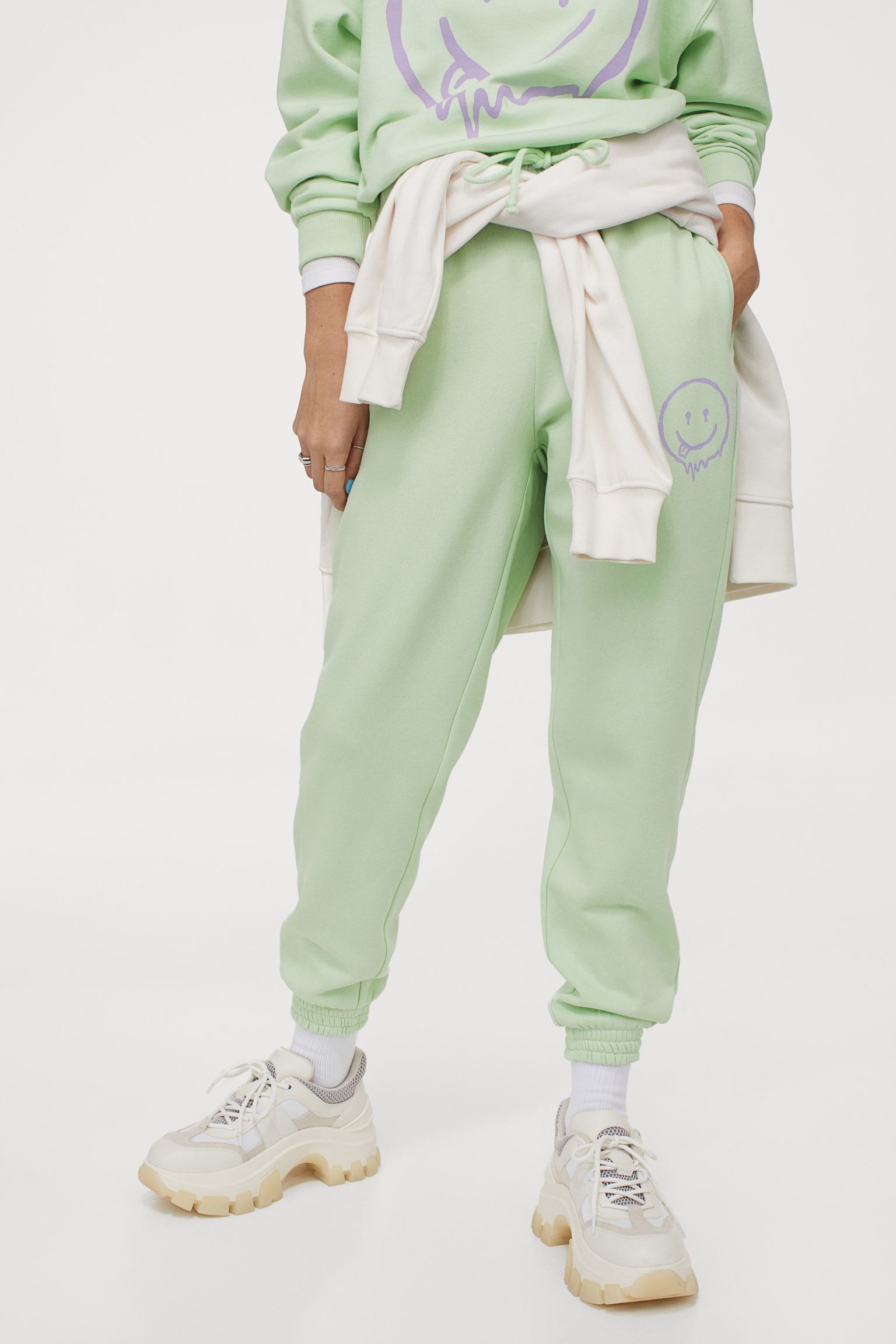 Model wearing the mint green sweatpants with a purple smiley face on the side
