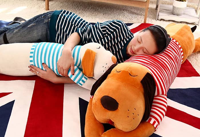 A person sleeping on a dog cushion while cuddling another.