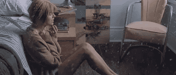 a gif of taylor swift sitting in a snowy bedroom in the &quot;back to december&quot; music video
