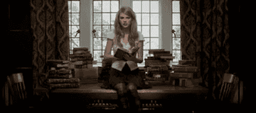 a gif of taylor swift closing a book in the &quot;story of us&quot; music video