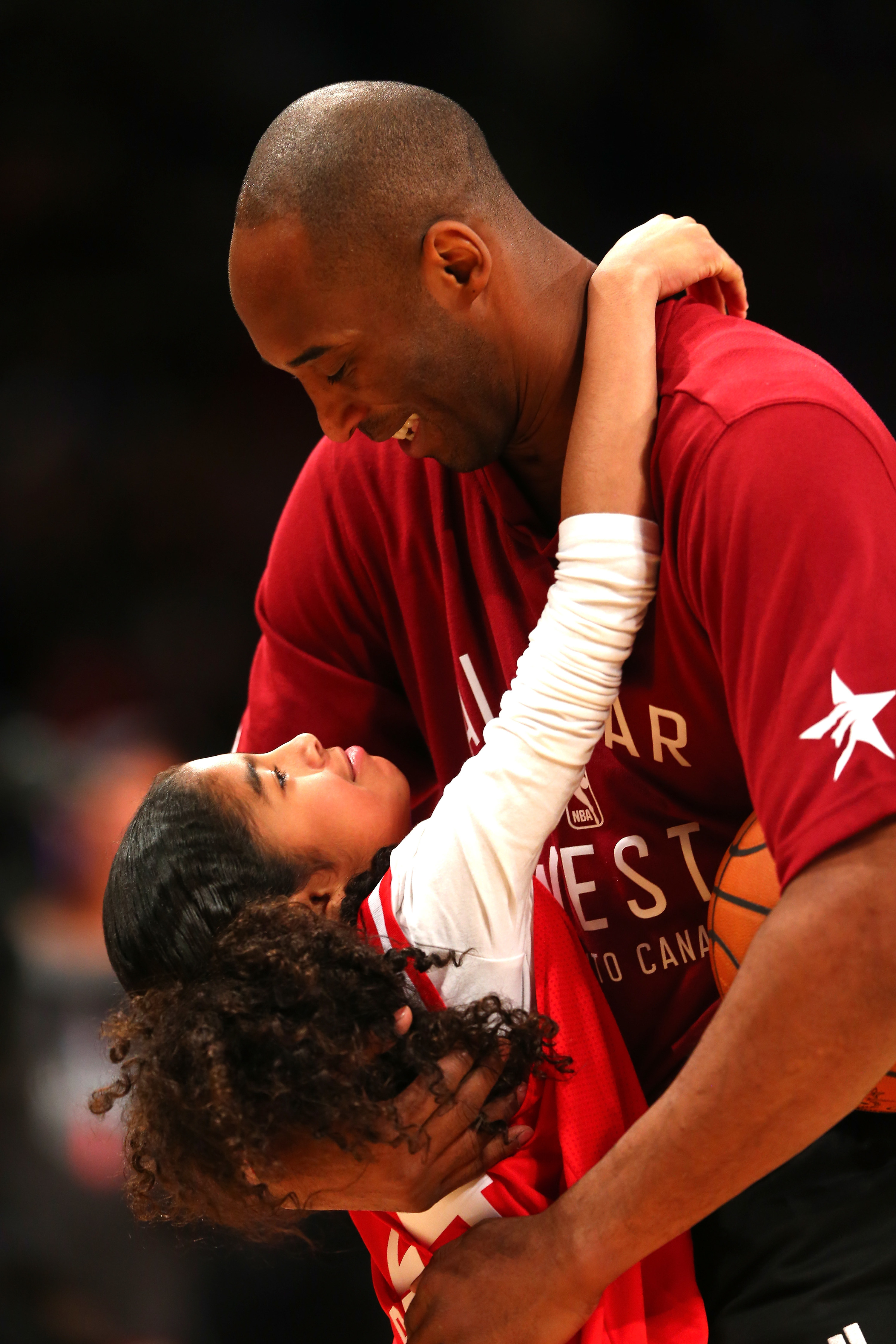 Kobe Bryant holding his daughter Gianna  and laughing with her as she looks up at him 