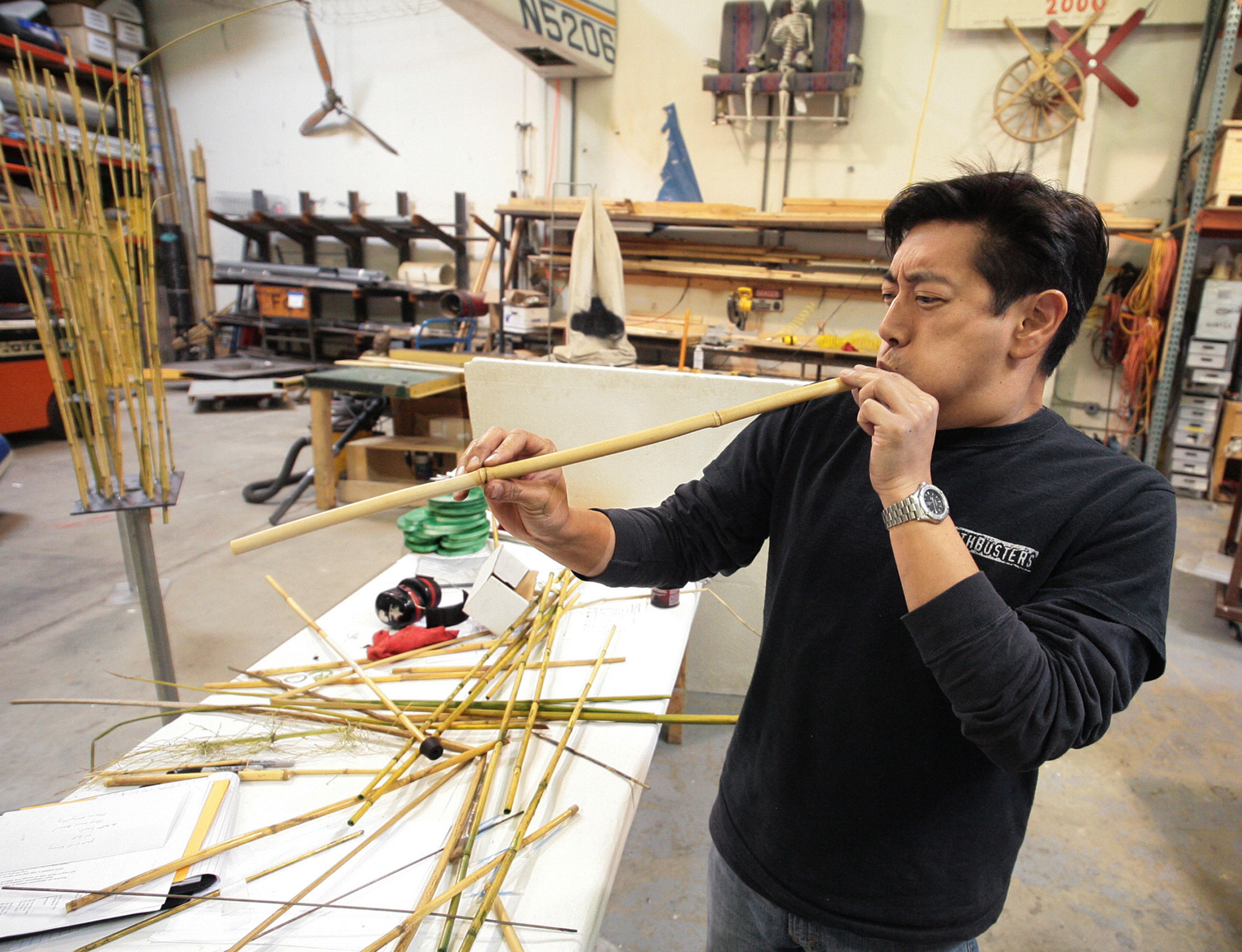 Man testing out a bamboo blowpipe in a workshop