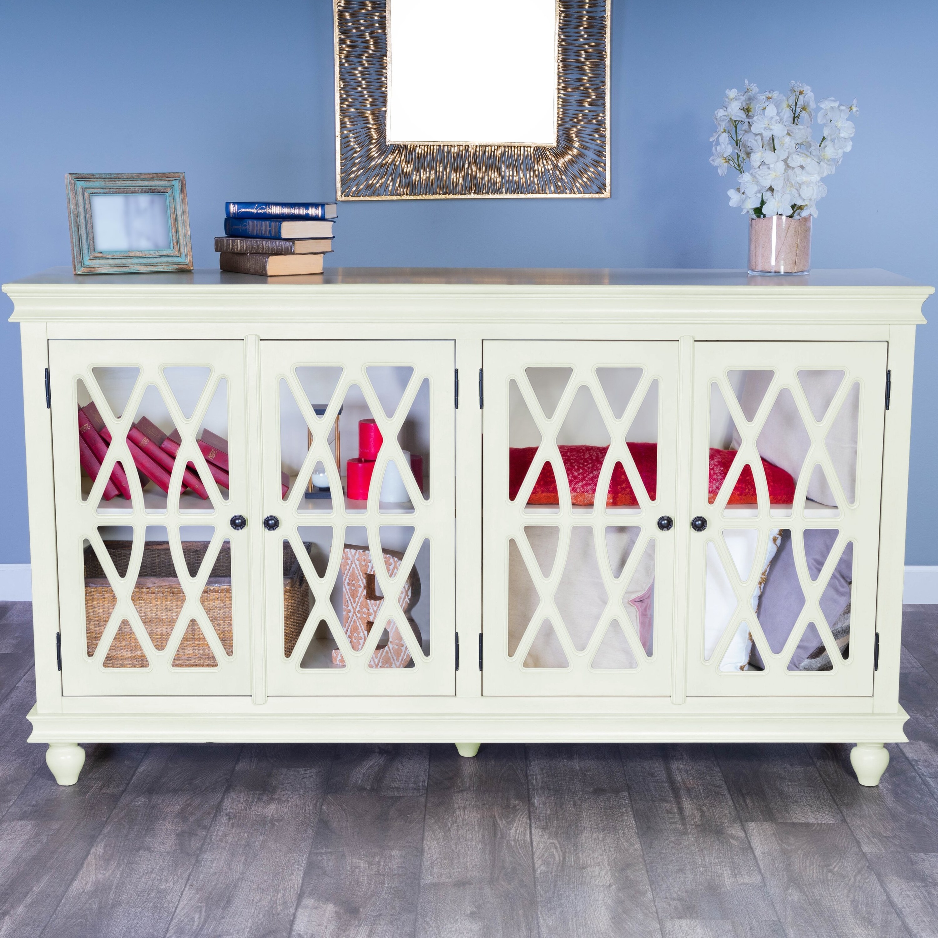 A white sideboard with mirror doors and a geometric trim with books and a frame on top