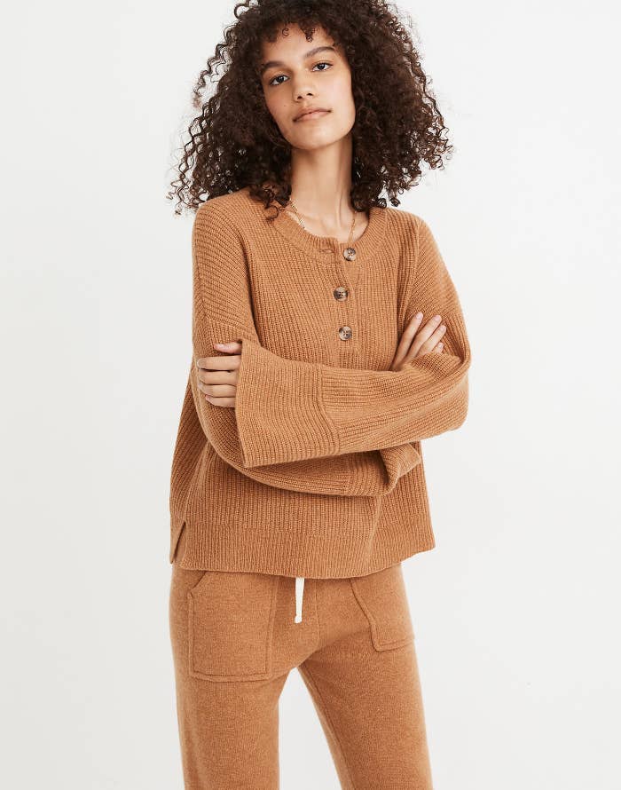 a model in a camel colored sweater with wide sleeves