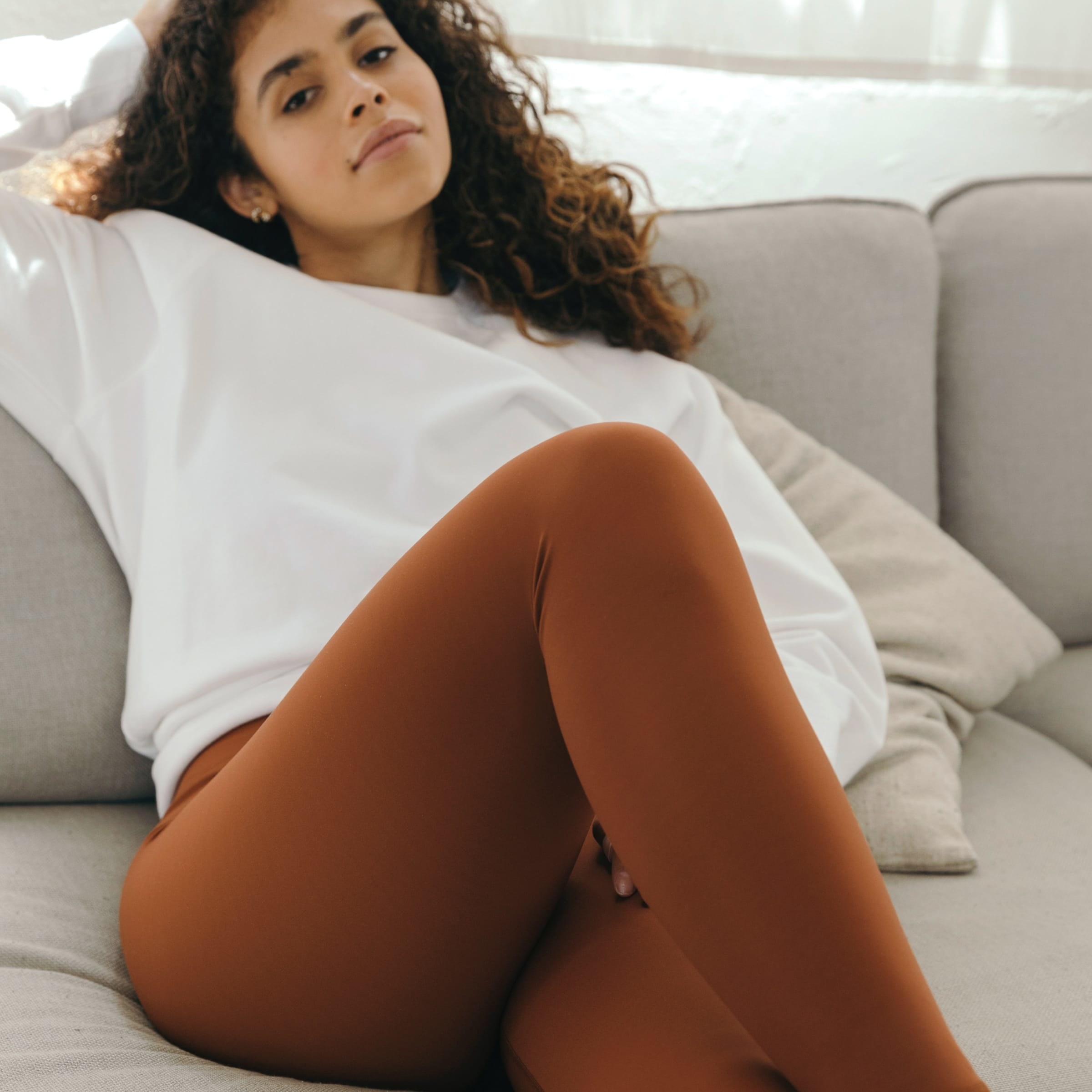 a model lounging in copper colored leggings