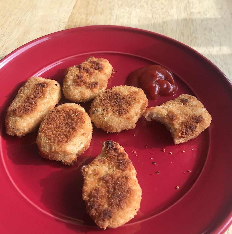 Chicken nuggets on a red plate with ketchup