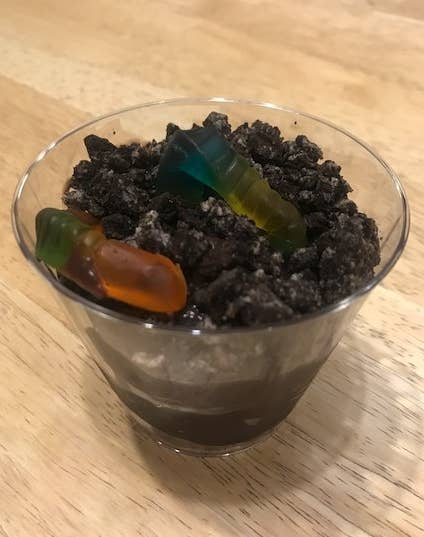 Clear cup of worms in dirt