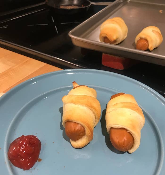 Ketchup and two pigs in a blanket on a plate