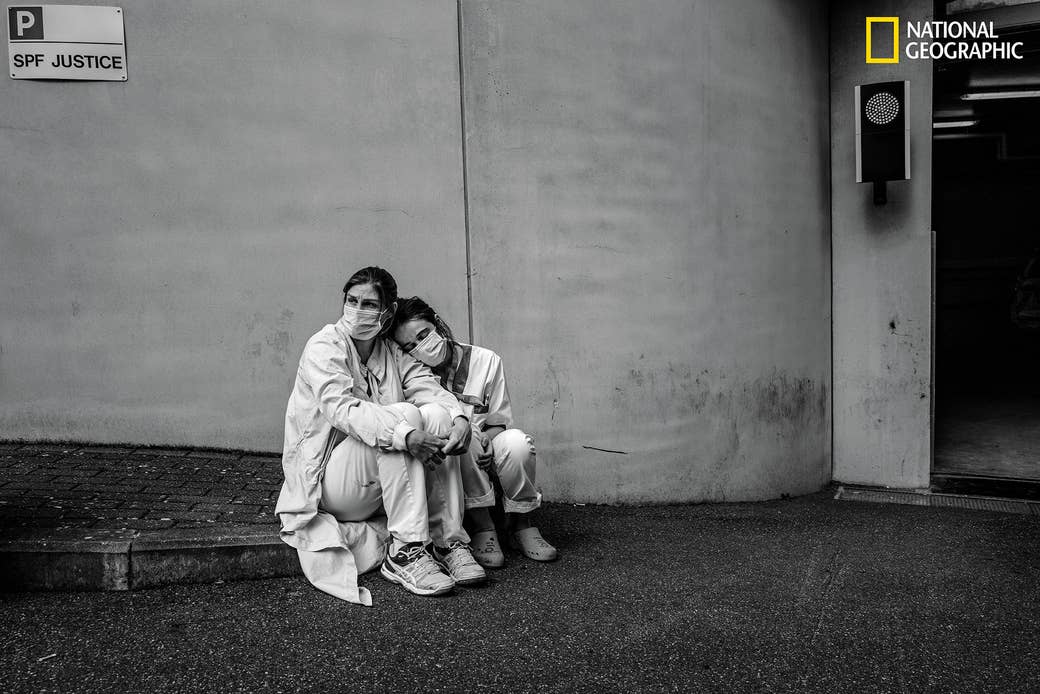 Two nurses in protective gear looking exhausted outside