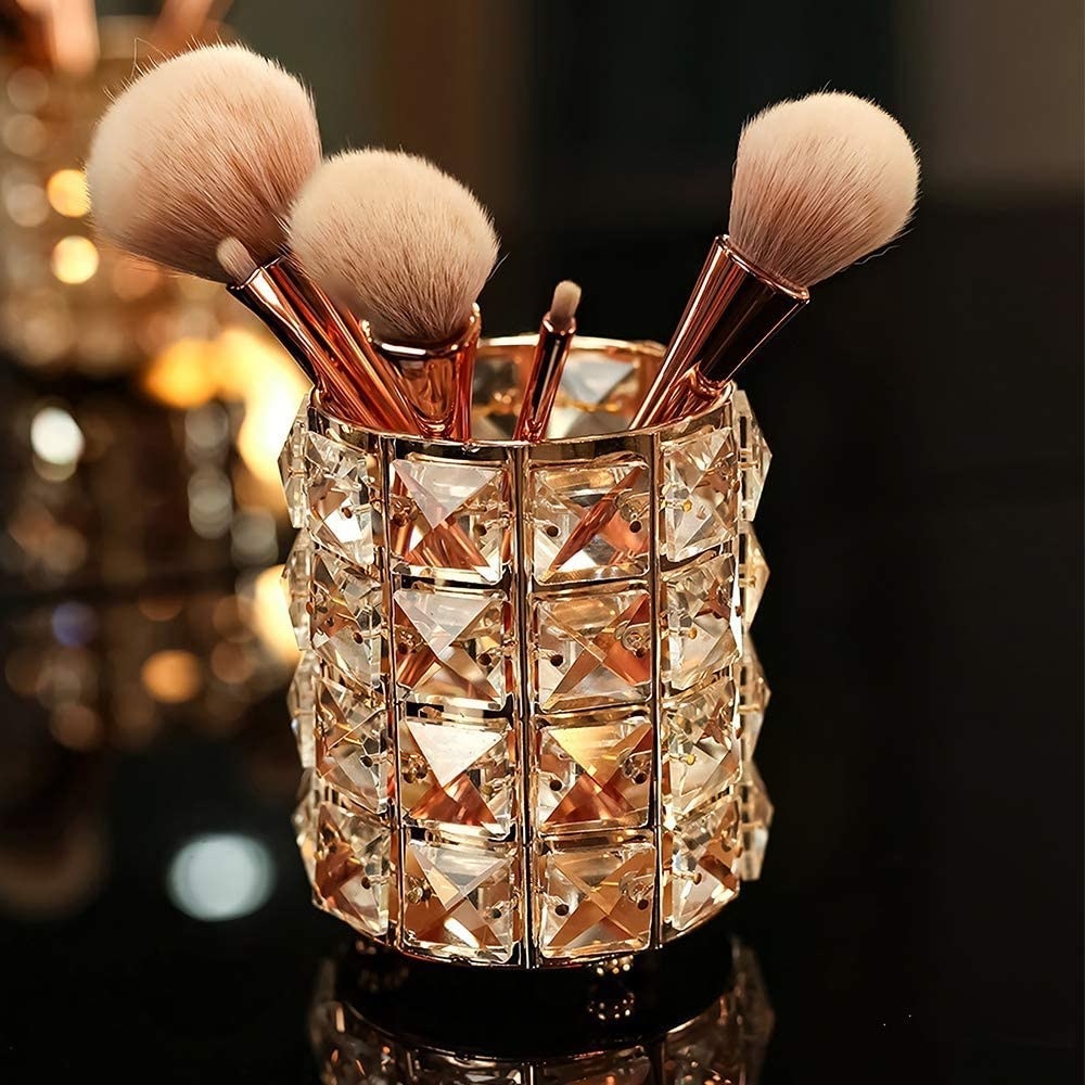 A jar lined with square crystals with makeup brushes poking out of it