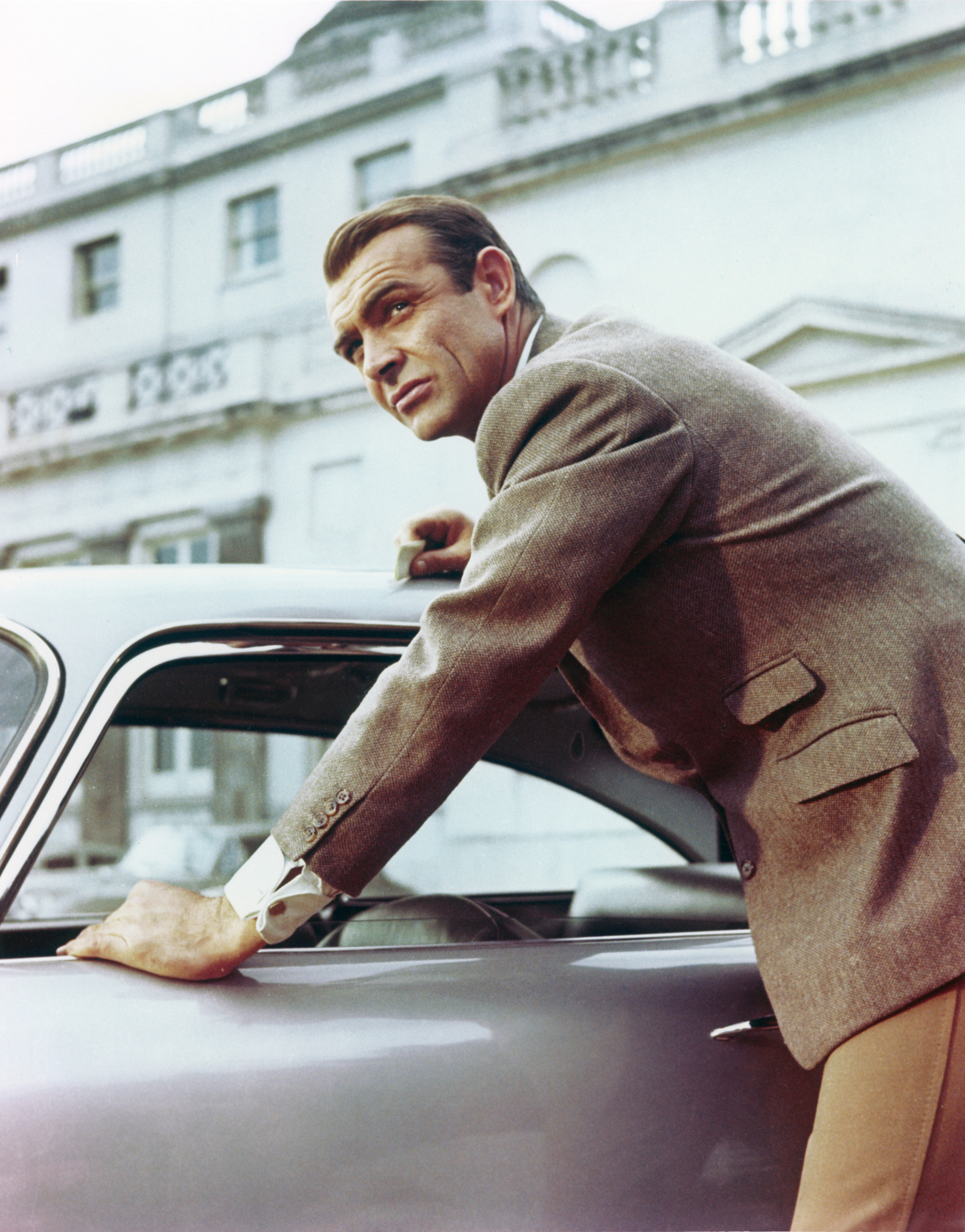 Sean Connery leaning on a car in a suit