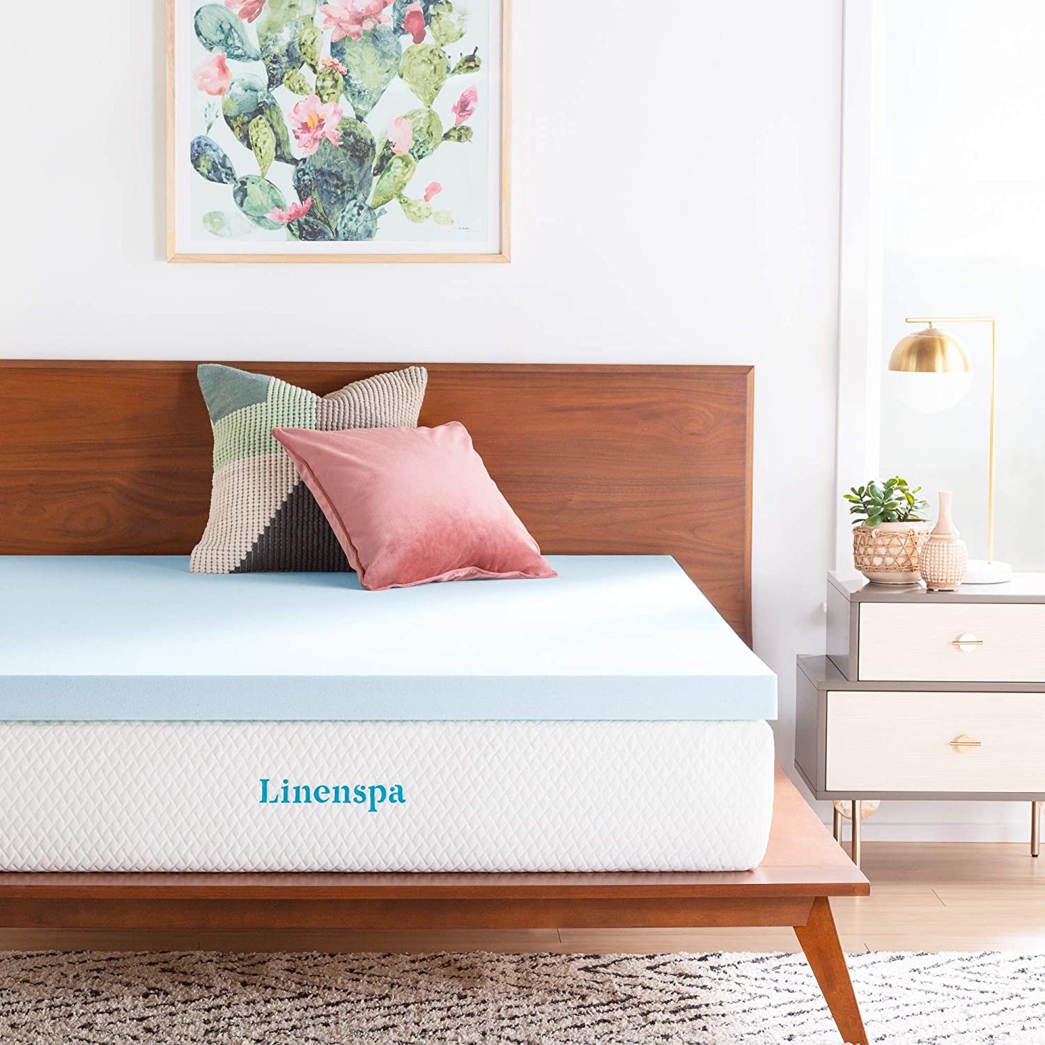 the memory foam mattress on top of a regular mattress with two pillows on a bed