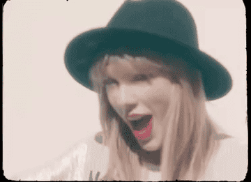 a gif of taylor swift holding up a 22 sign with her hands while singing in the &quot;22&quot; music video