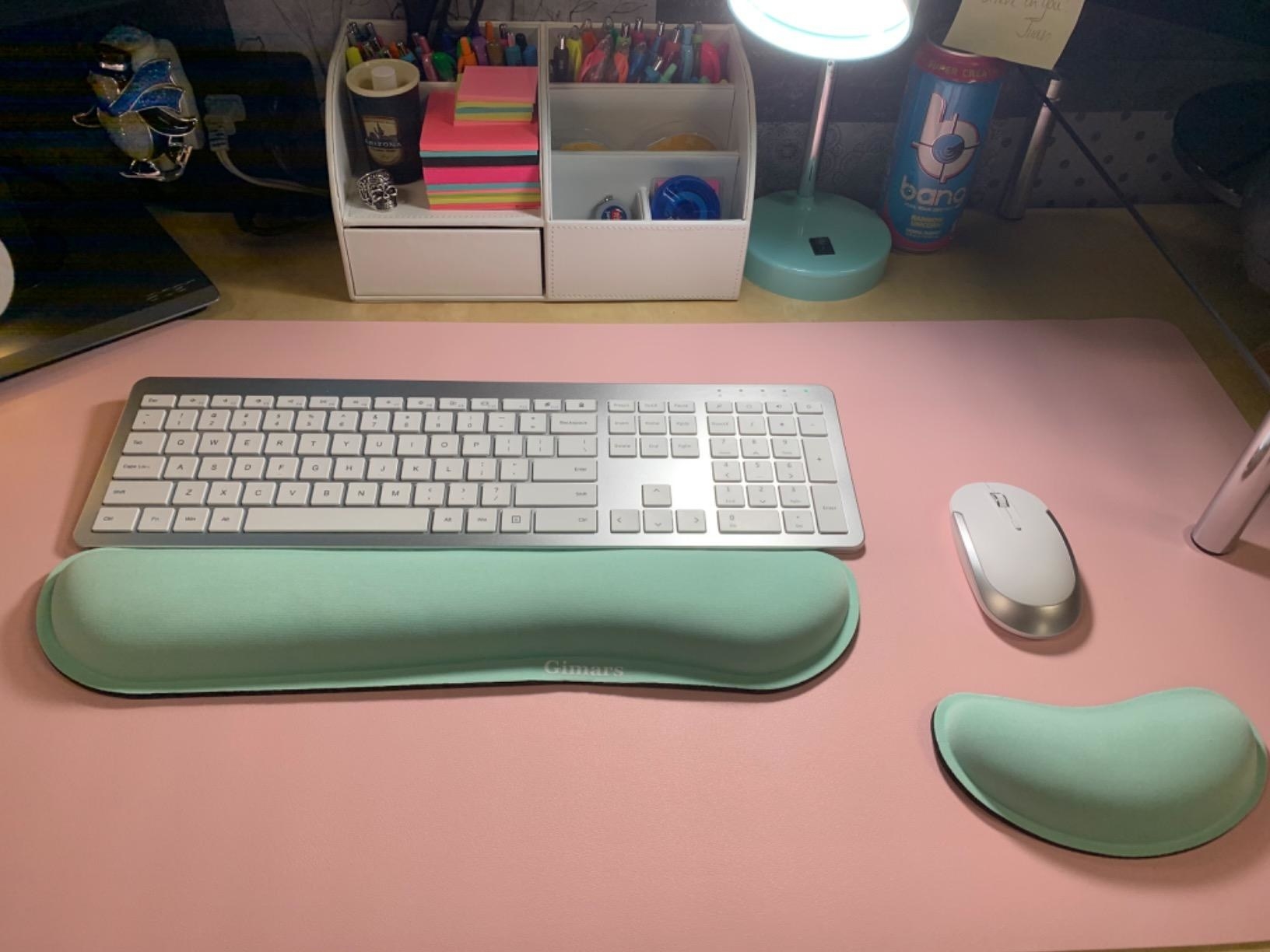 A reviewer&#x27;s computer set up with the mint green keyboard and mouse wrist support pads