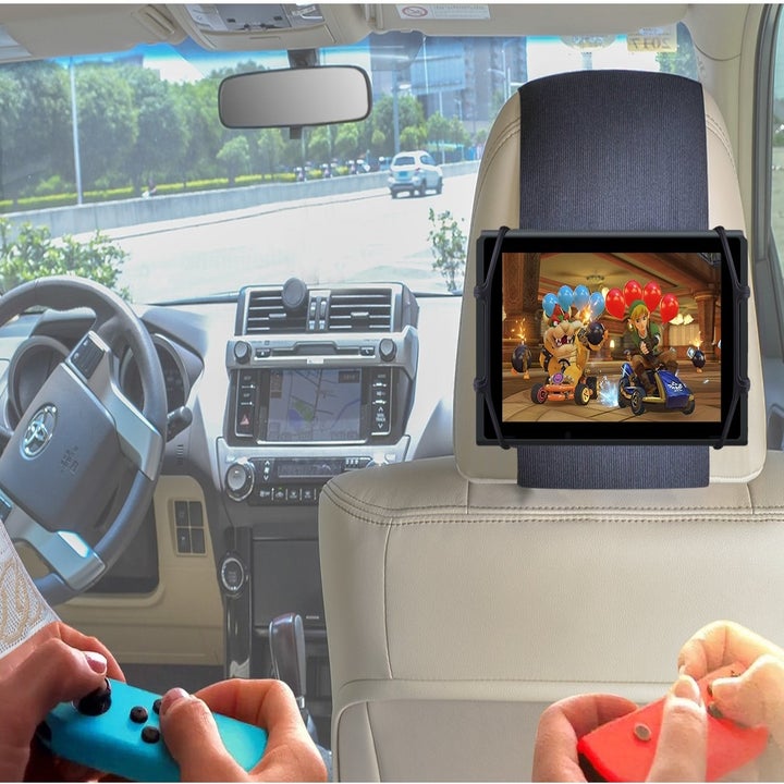Models holding Nintendo Switch joy-cons with screen placed in headrest mount