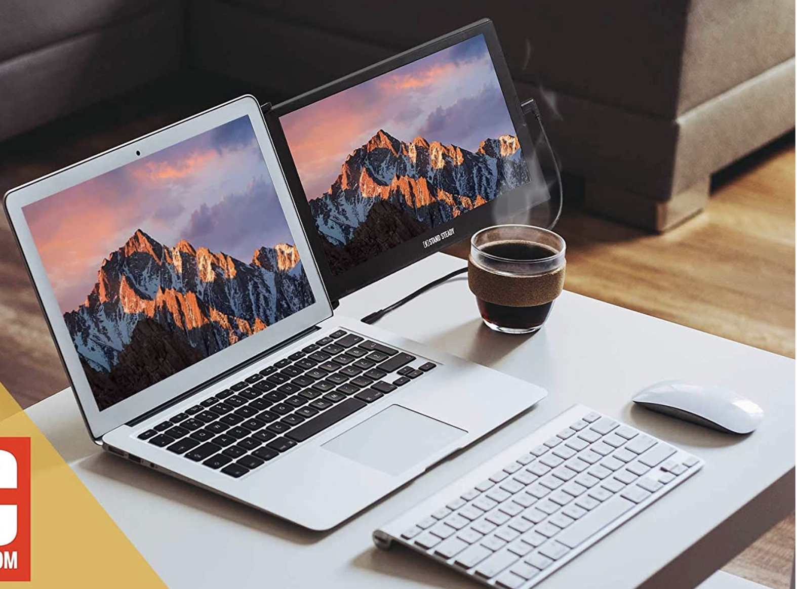 A laptop with a small black monitor attached to the existing monitor on a desk 