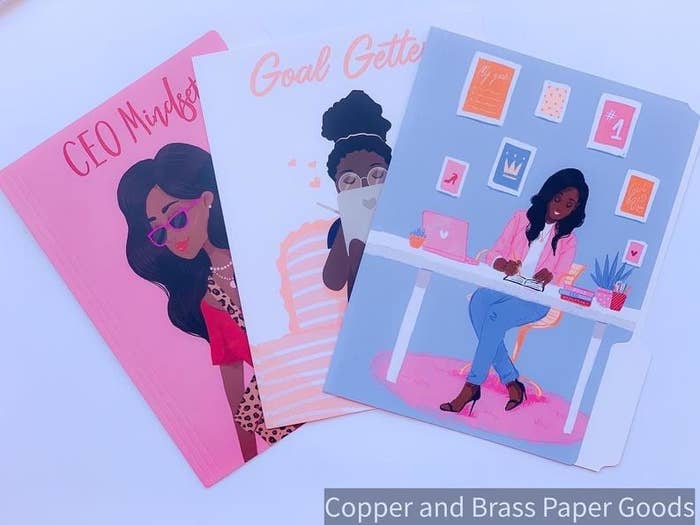 The three folders: a pink one with a stylishly dressed woman and the text &quot;CEO mindset,&quot; a light blue one with a woman working on a tablet in bed and the text &quot;goal getter,&quot; and a blue one with a woman working in an adorably decorated office