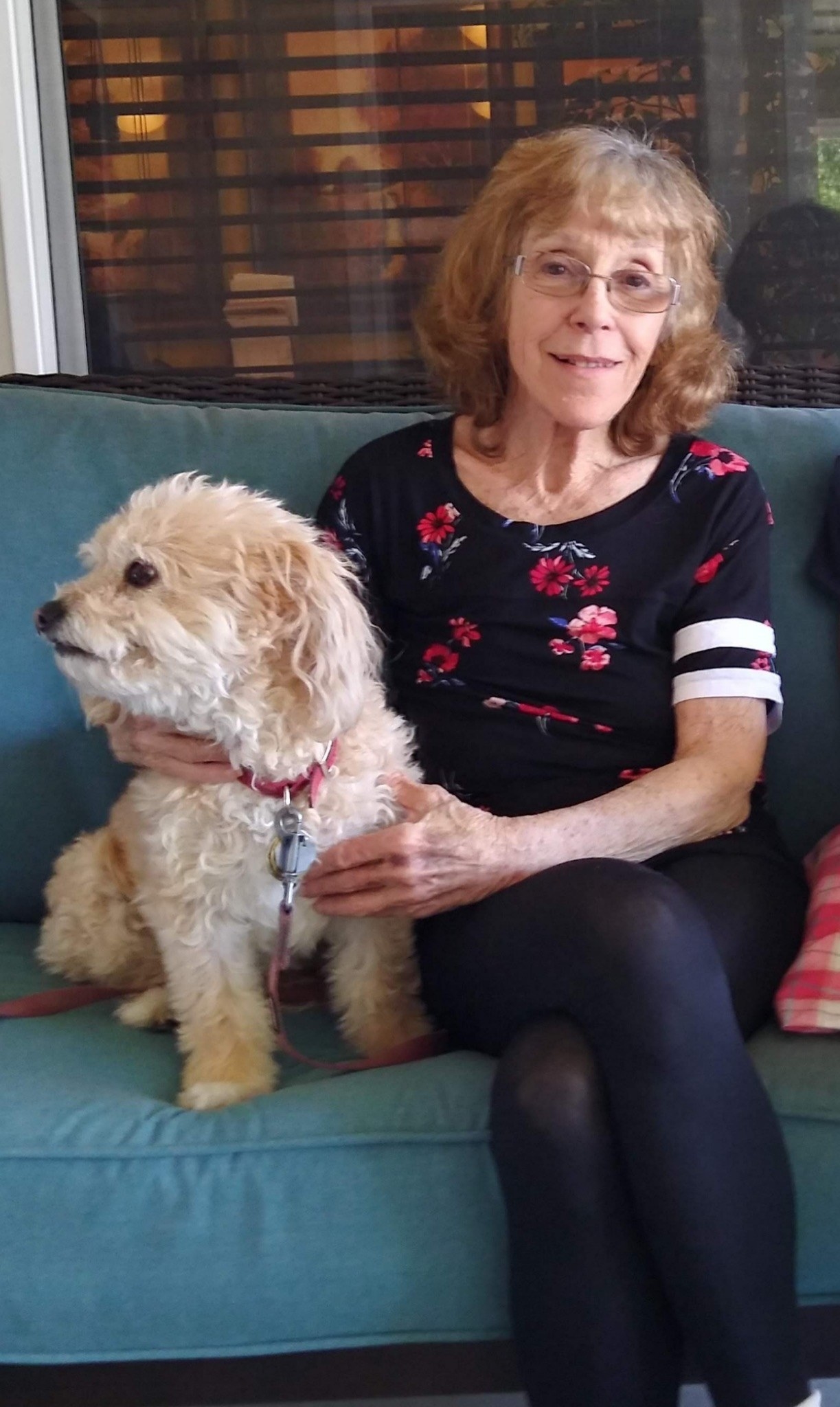 Soleil sits on a couch with her dog, who looks away to their right