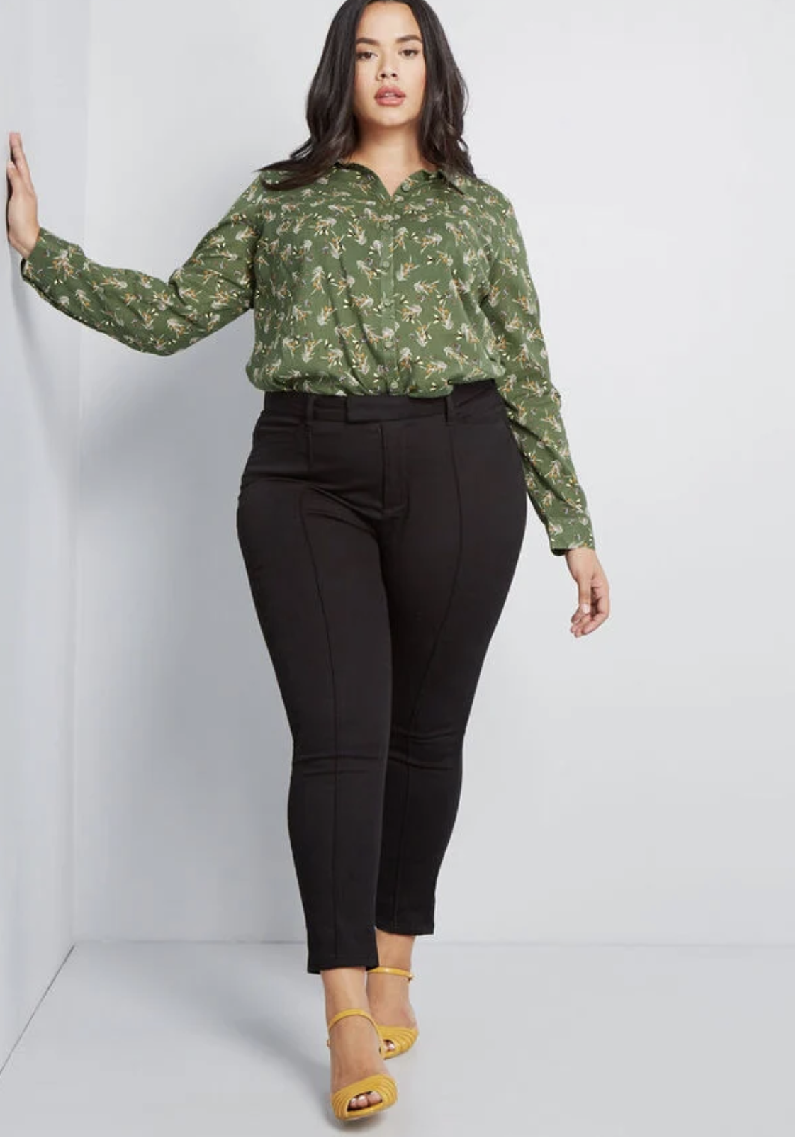 Model in a pair of black highwaisted ankle pants with a seam down the middle of each leg 