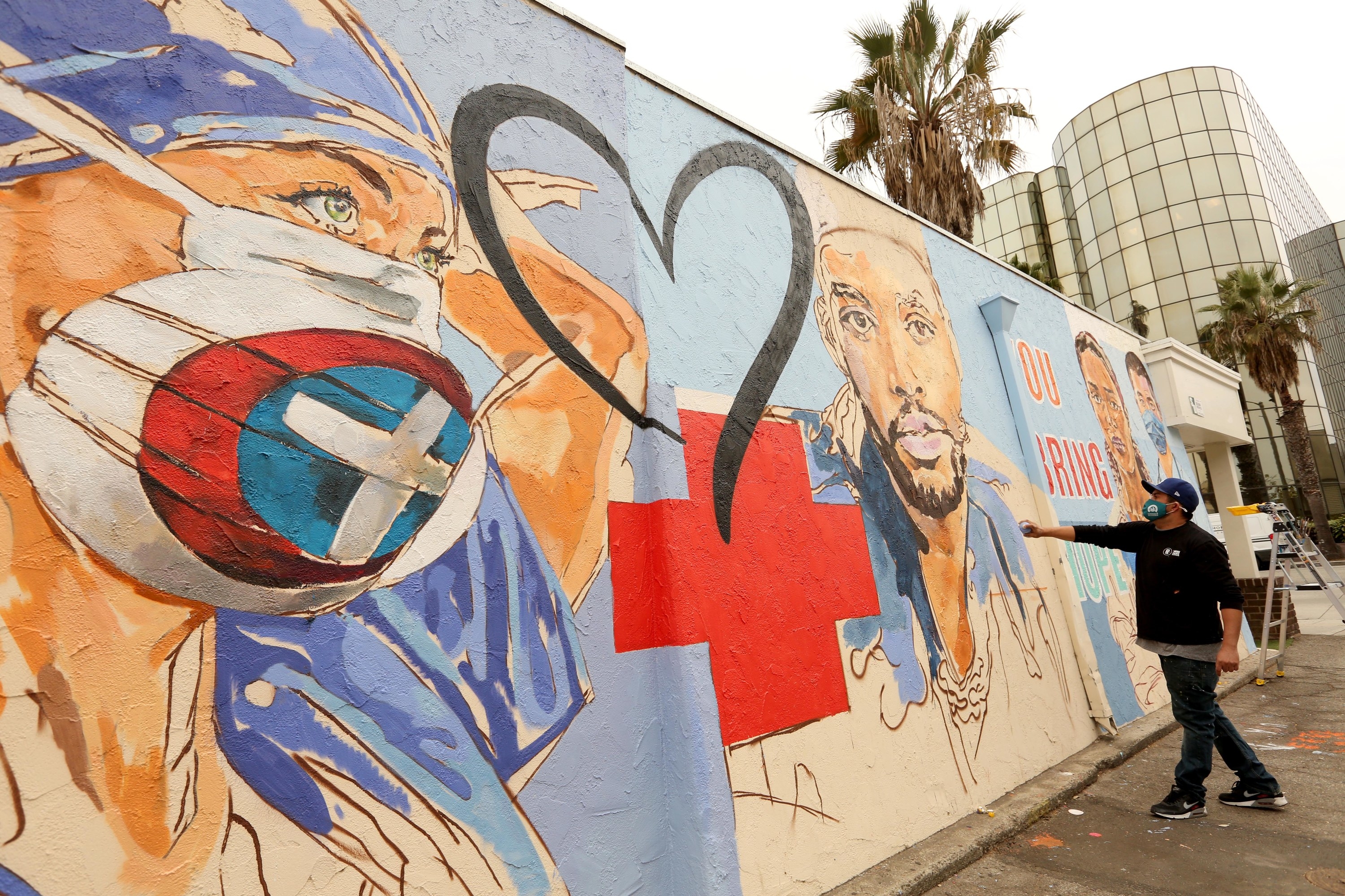 A street mural shows a red cross and heart between illustrations of healthcare workers