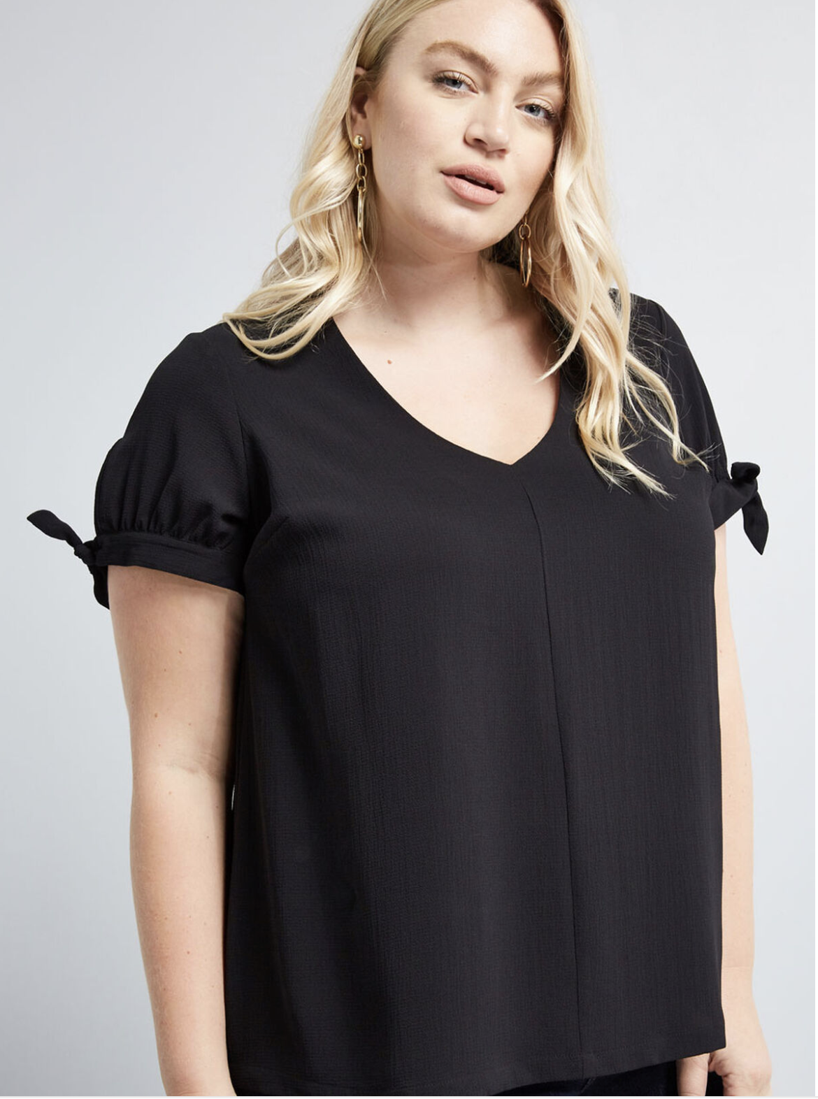 Model in black V-neck top with short sleeves and a seam down the middle 