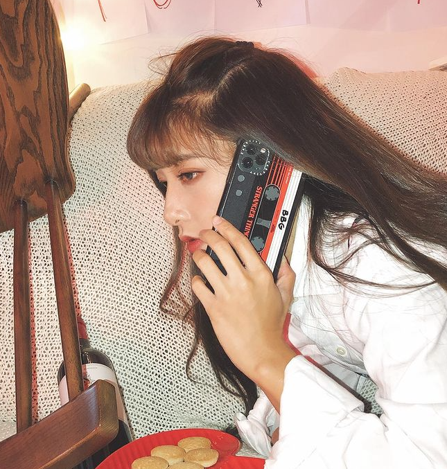 A woman holding her iPhone in a phone case that looks like a 1980s mixtape