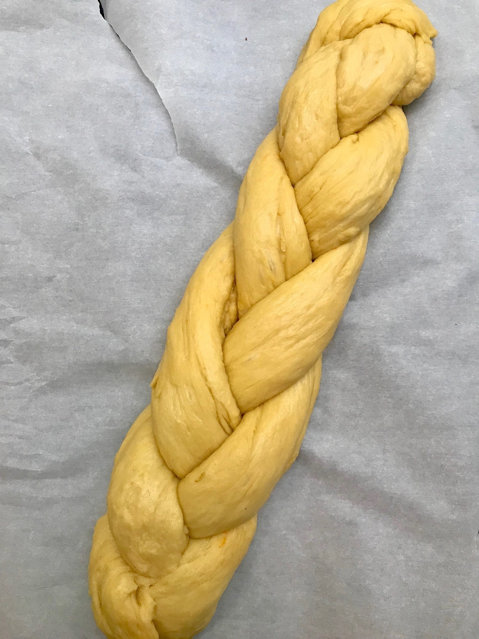 A braided loaf of challah, ready to be baked.