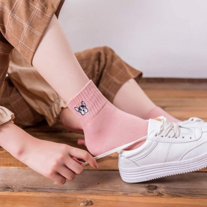 Model wearing the socks that come to the top of the ankle with an embroidered Frenchie face on the top in pink