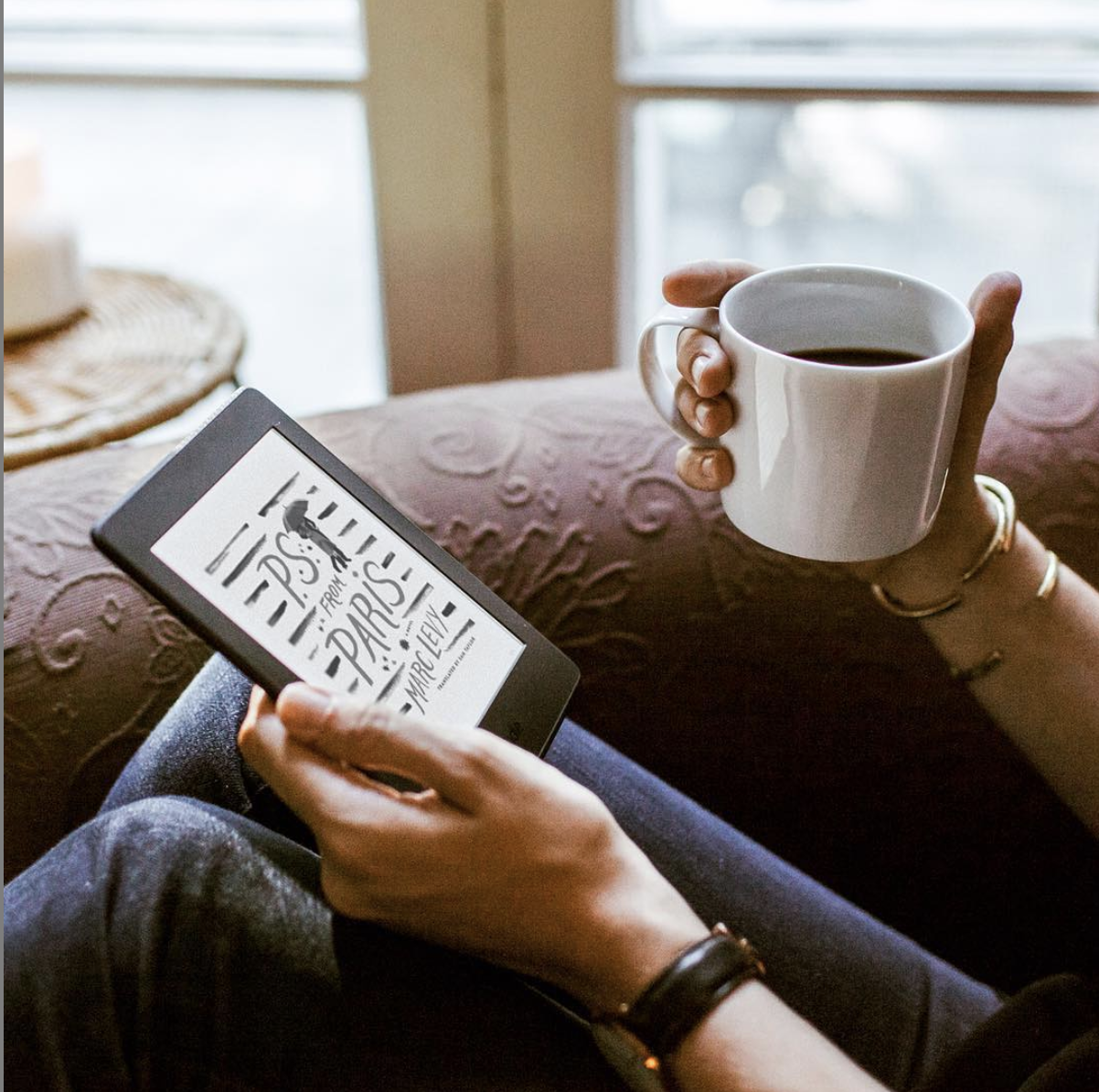person reading using the kindle with a cup of coffee